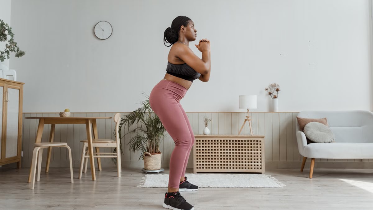Black woman exercising at home in stylish activewear, promoting a healthy lifestyle.